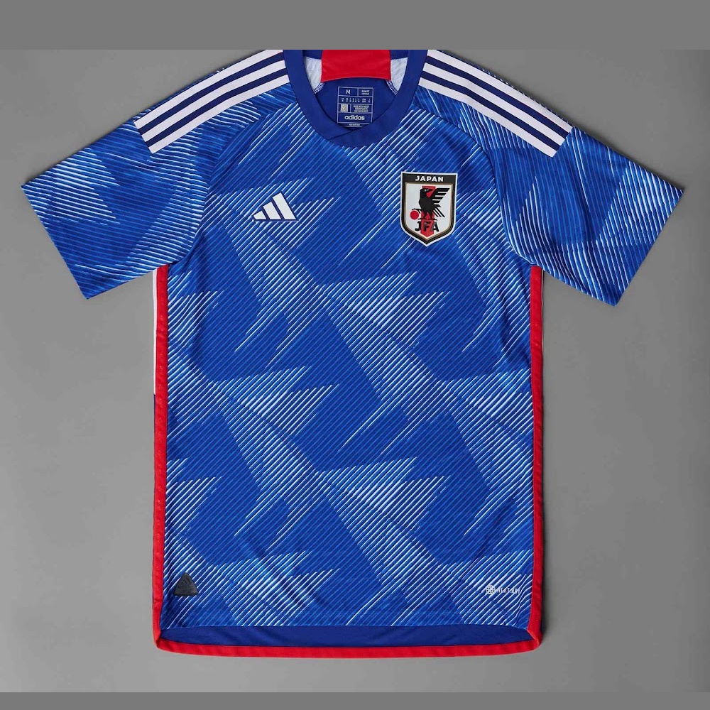 The 2022 home shirt shows the design logic clearly: sharp blue pattern, white detail, and a controlled match-day rhythm.